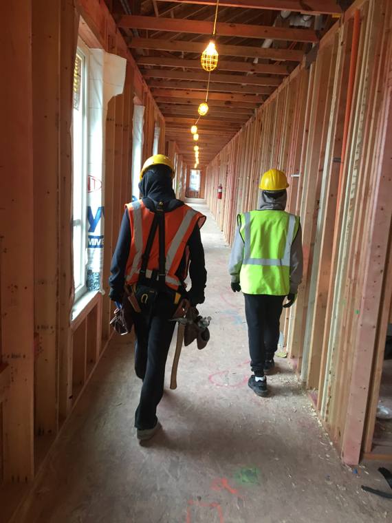 Framers walking a framed hallway inside a multi-family build